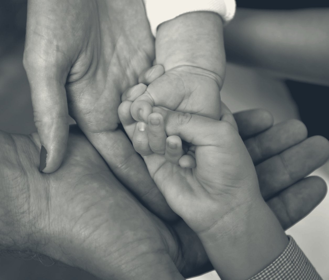 Two parents and their newborn joining hands